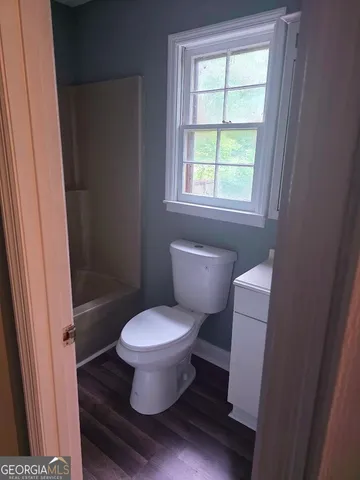 a white toilet sitting next to a window in a bathroom