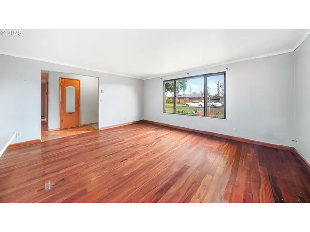 a open hall with a hardwood floor and window