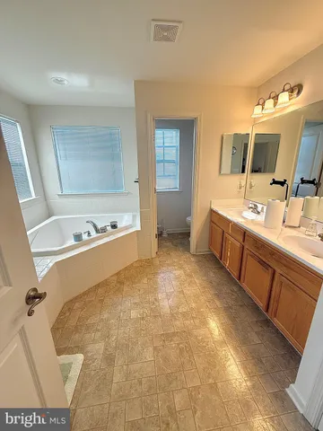 a spacious bathroom with a tub sink and mirror