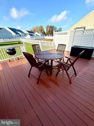 a view of a patio with table and chairs with wooden floor and fence