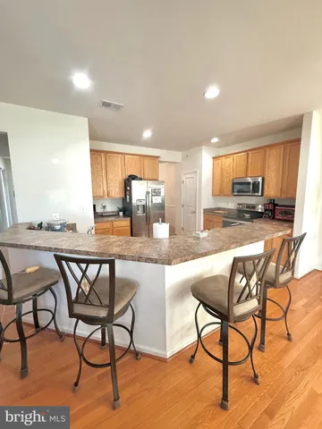 a kitchen with stainless steel appliances granite countertop table chairs sink and window