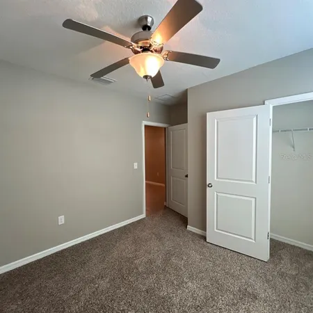 an empty room with closet and a chandelier fan