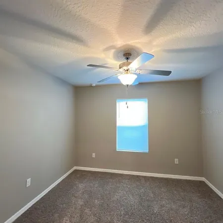 an empty room with windows and chandelier fan