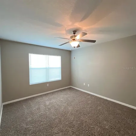 an empty room with windows and fan