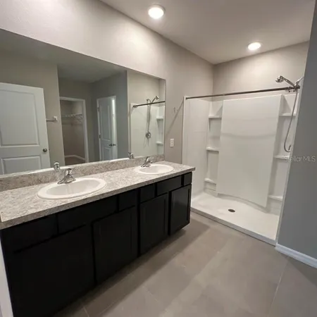 a bathroom with a tub a double vanity sink and mirror