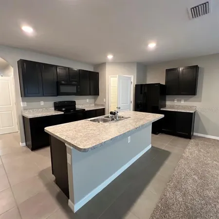 a large kitchen with kitchen island a sink dishwasher a stove and a microwave oven with cabinets