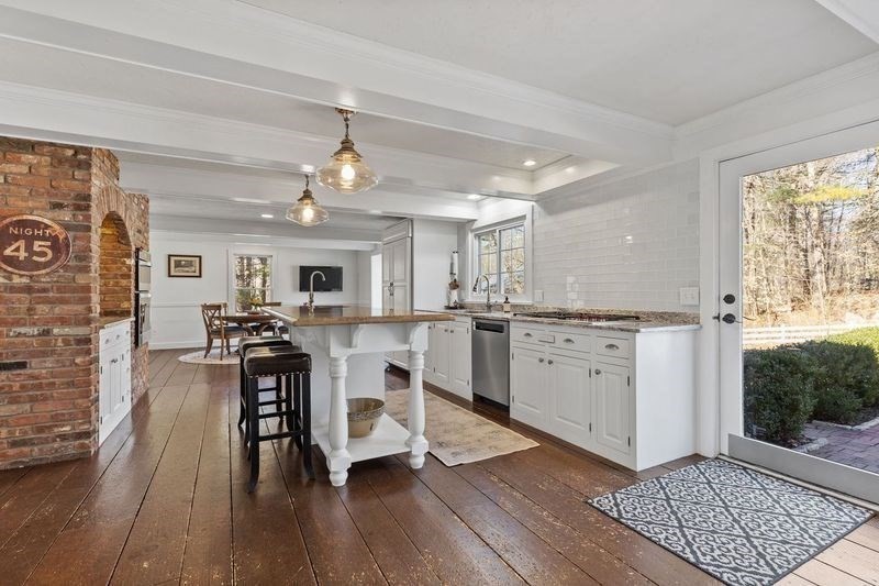 57 Whitewood Road Milford, MA 01757 - Photo 3 of 40 a kitchen with stainless steel appliances granite countertop a stove top oven a refrigerator a dining table and chairs with wooden floor