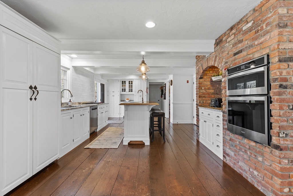 57 Whitewood Road Milford, MA 01757 - Photo 9 of 40 a kitchen with stainless steel appliances kitchen island granite countertop a refrigerator a stove oven and white cabinets with wooden floors