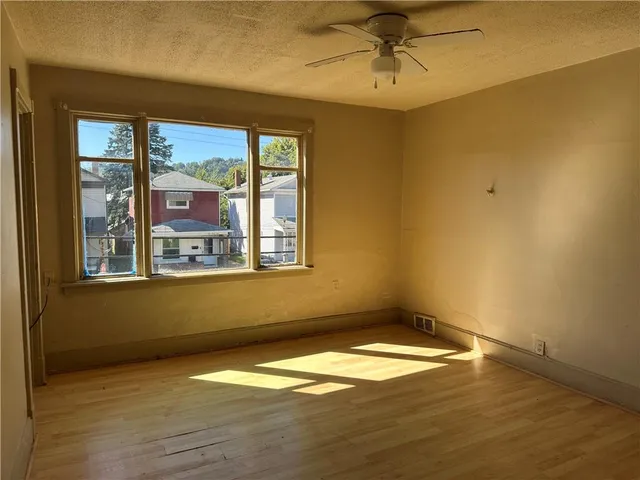 a view of empty room with wooden floor and fan