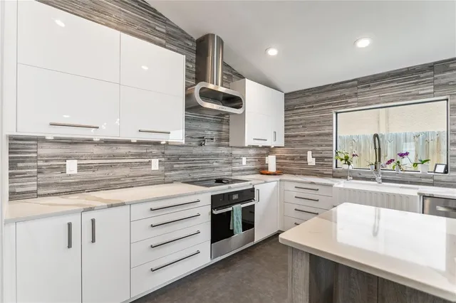 a kitchen with stainless steel appliances granite countertop a stove a sink and white cabinets