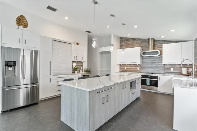 a large kitchen with stainless steel appliances granite countertop a sink and a refrigerator