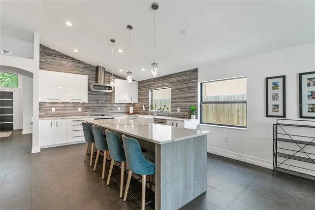 a kitchen with kitchen island a sink a stove a refrigerator cabinets and a dining table