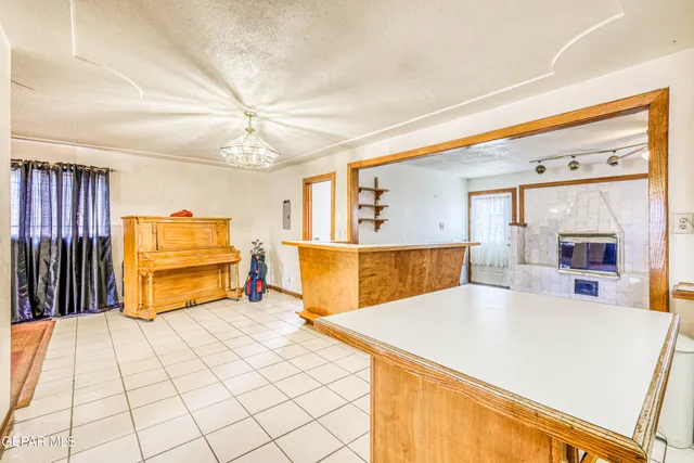 a view of an empty room with window and chandelier fan