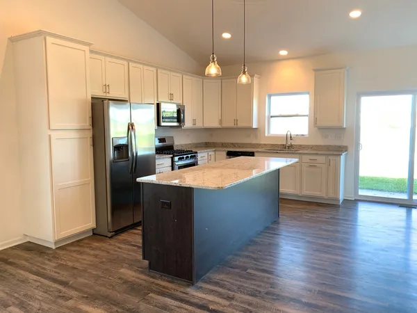 a kitchen with kitchen island a sink a center island stainless steel appliances and cabinets