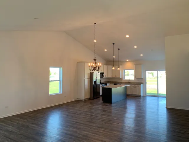 a kitchen with a kitchen island a sink wooden floor and a view of living room