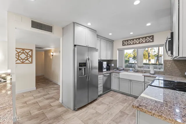 a kitchen with stainless steel appliances kitchen island granite countertop a stove a sink and a refrigerator