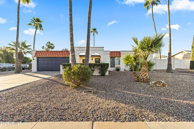 a view of an outside dining space with a table and chairs under an umbrella