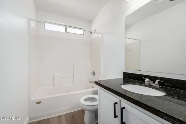 a bathroom with a granite countertop sink a toilet a mirror a bathtub and shower