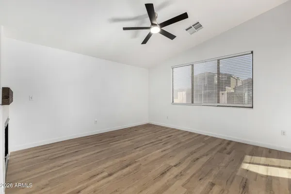 a view of empty room with wooden floor and fan