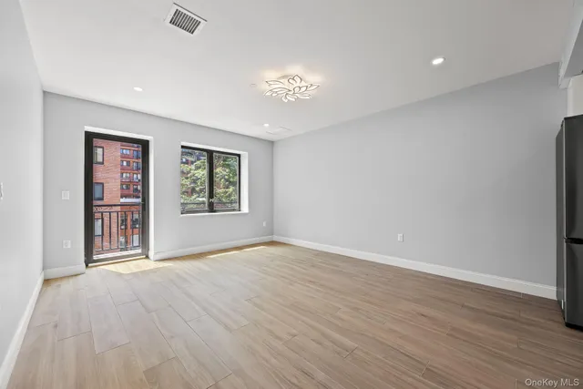 an empty room with wooden floor chandelier and windows
