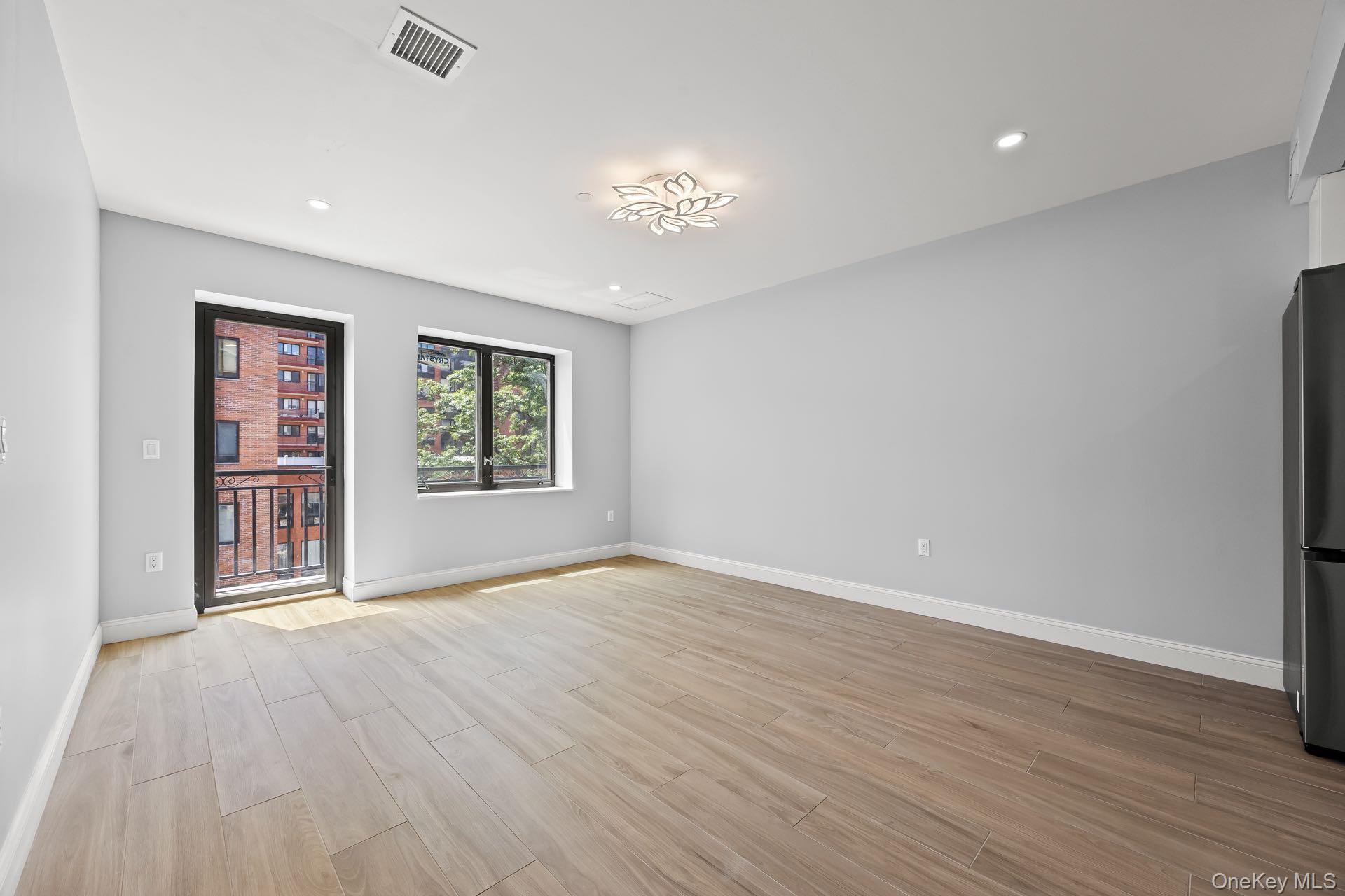 132-25 41st Avenue, Unit 3A Queens, NY 11355 - Photo 2 of 12 an empty room with wooden floor chandelier and windows