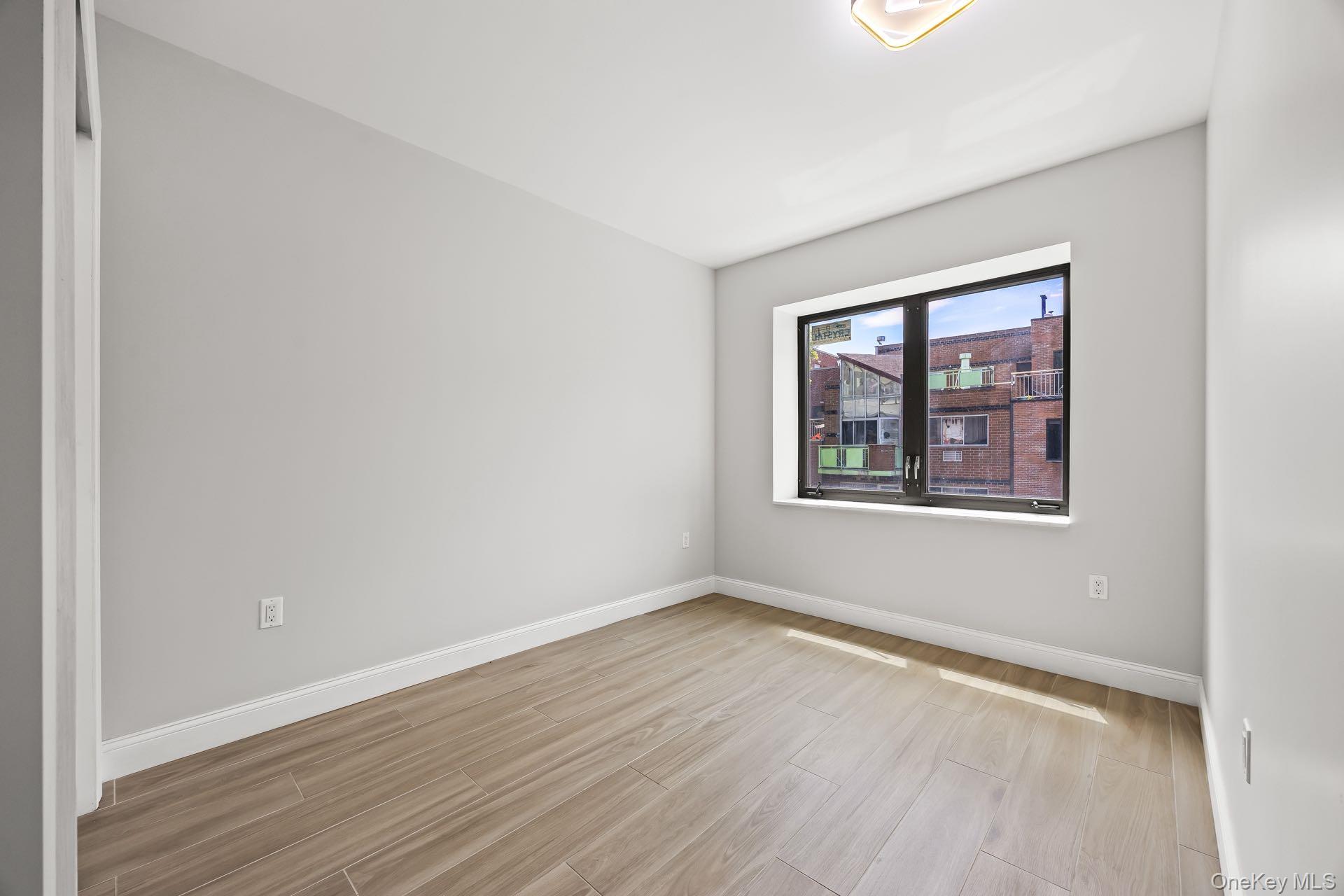 132-25 41st Avenue, Unit 3A Queens, NY 11355 - Photo 8 of 12 an empty room with wooden floor and windows