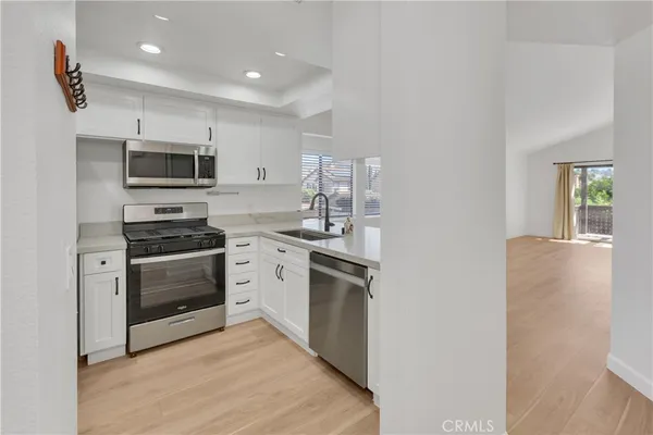 a kitchen with stainless steel appliances white cabinets and a stove top oven