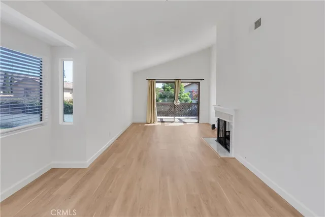 an empty room with floor to ceiling window and fireplace