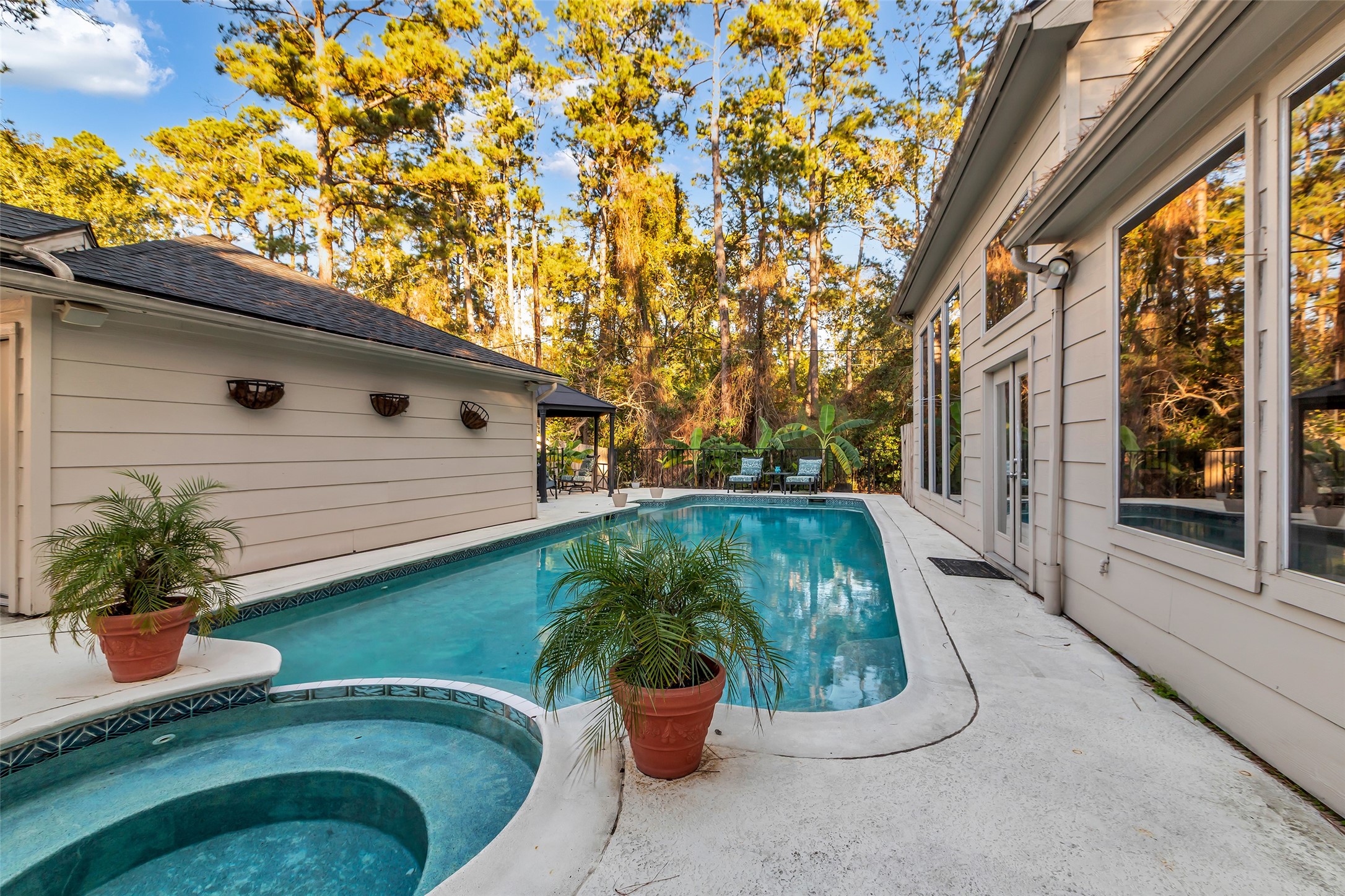24102 Northcrest Drive Spring, TX 77389 - Photo 27 of 31 This stunning backyard oasis features a luxurious pool and inviting hot tub, nestled against a backdrop of lush trees for ultimate relaxation and privacy.