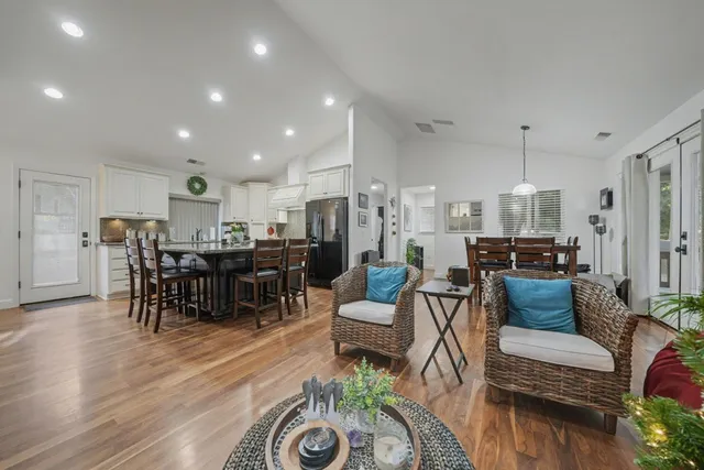 a living room with furniture and a dining table with wooden floor
