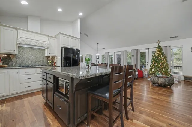 a kitchen with stainless steel appliances granite countertop a table chairs sink and wooden floor