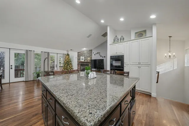 an open kitchen with granite countertop kitchen island wooden floor center island and stainless steel appliances