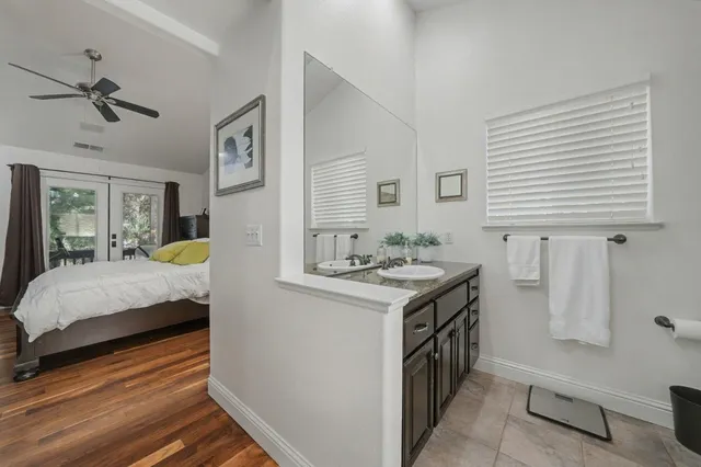 a en suite bathroom with a granite countertop sink and a large mirror