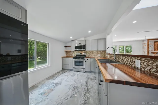 a kitchen with stainless steel appliances granite countertop a stove a sink and a microwave