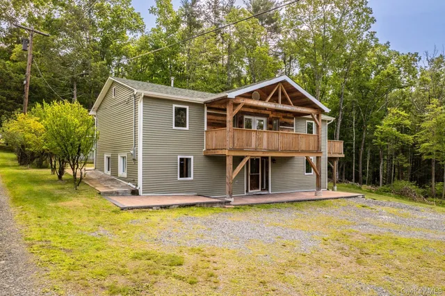 a front view of house with yard and trees in the background