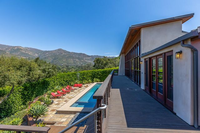 a balcony with tall trees and a view of an outdoor swimming pool