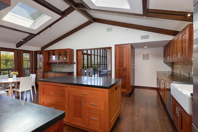 a kitchen with stainless steel appliances kitchen island granite countertop a refrigerator a stove and a sink with wooden cabinets