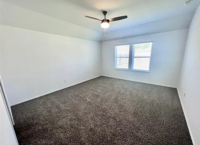 an empty room with windows and ceiling fan