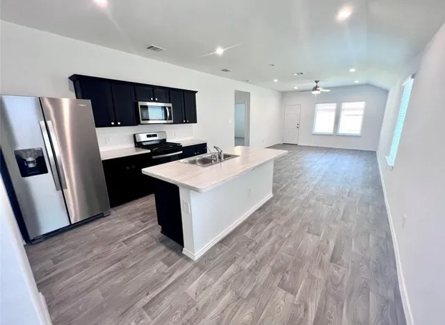 a kitchen with stainless steel appliances a refrigerator sink and wooden floor