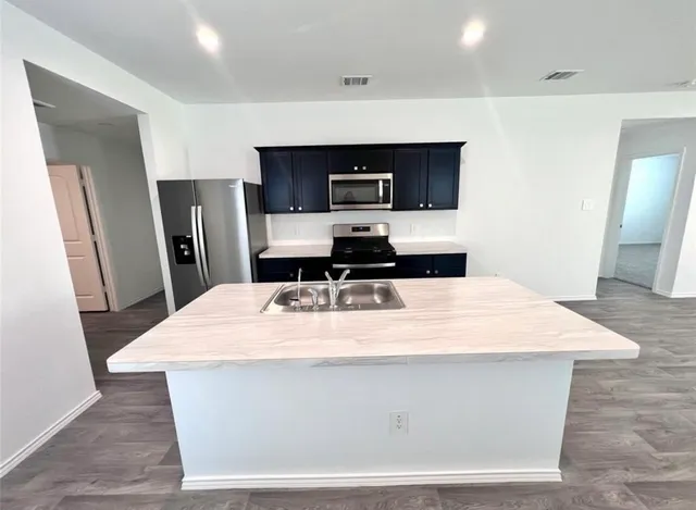 a room with stainless steel appliances kitchen island sink refrigerator and stove