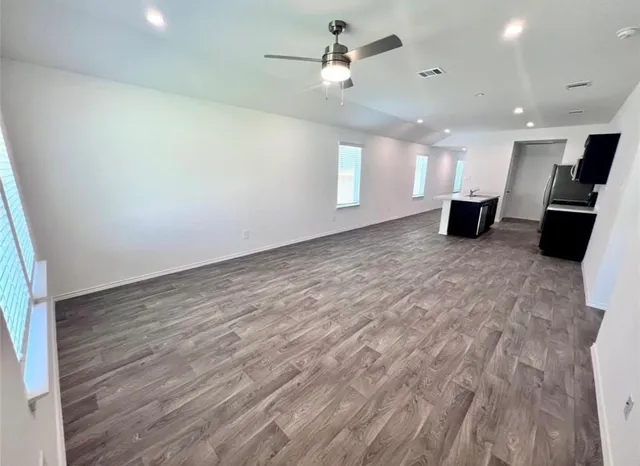 an empty room with wooden floor and ceiling fan