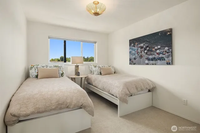 a spacious bedroom with two beds and a painting on the wall