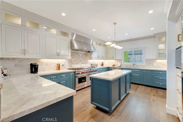 a large kitchen with stainless steel appliances granite countertop a stove a sink dishwasher and a refrigerator with wooden floor