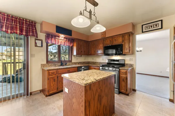 a kitchen with stainless steel appliances kitchen island granite countertop a sink refrigerator and cabinets