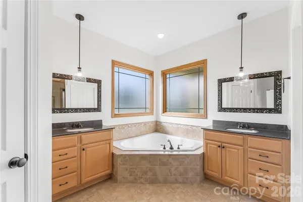 a bathroom with a granite countertop sink a mirror a bathtub and window