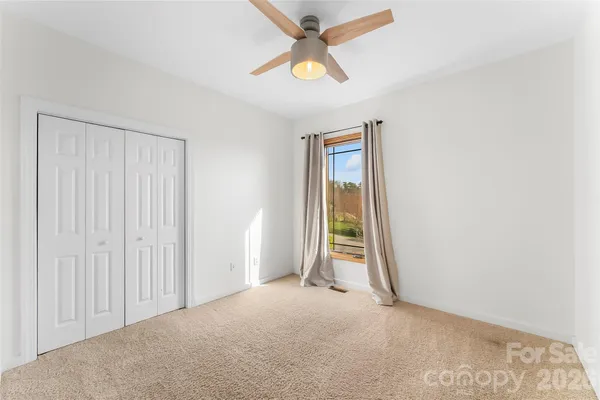 an empty room with closet and a chandelier fan