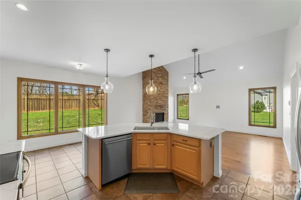 a large kitchen with kitchen island a large window a sink stainless steel appliances and cabinets