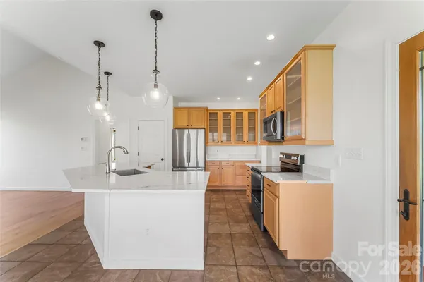 a large room with kitchen island a sink a counter top space and cabinets