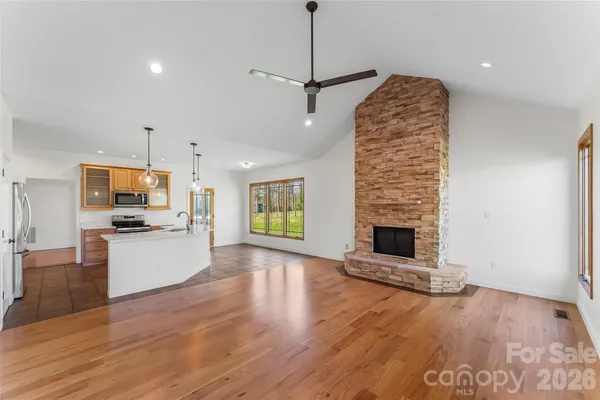 a open kitchen with granite countertop a stove top oven a sink a counter space and wooden floor
