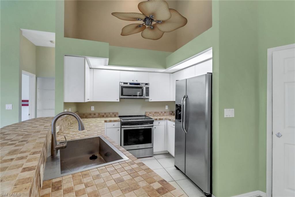 481 Raven Way Naples, FL 34110 - Photo 8 of 30 a kitchen with stainless steel appliances granite countertop a sink a stove a refrigerator cabinets a dining table and chairs